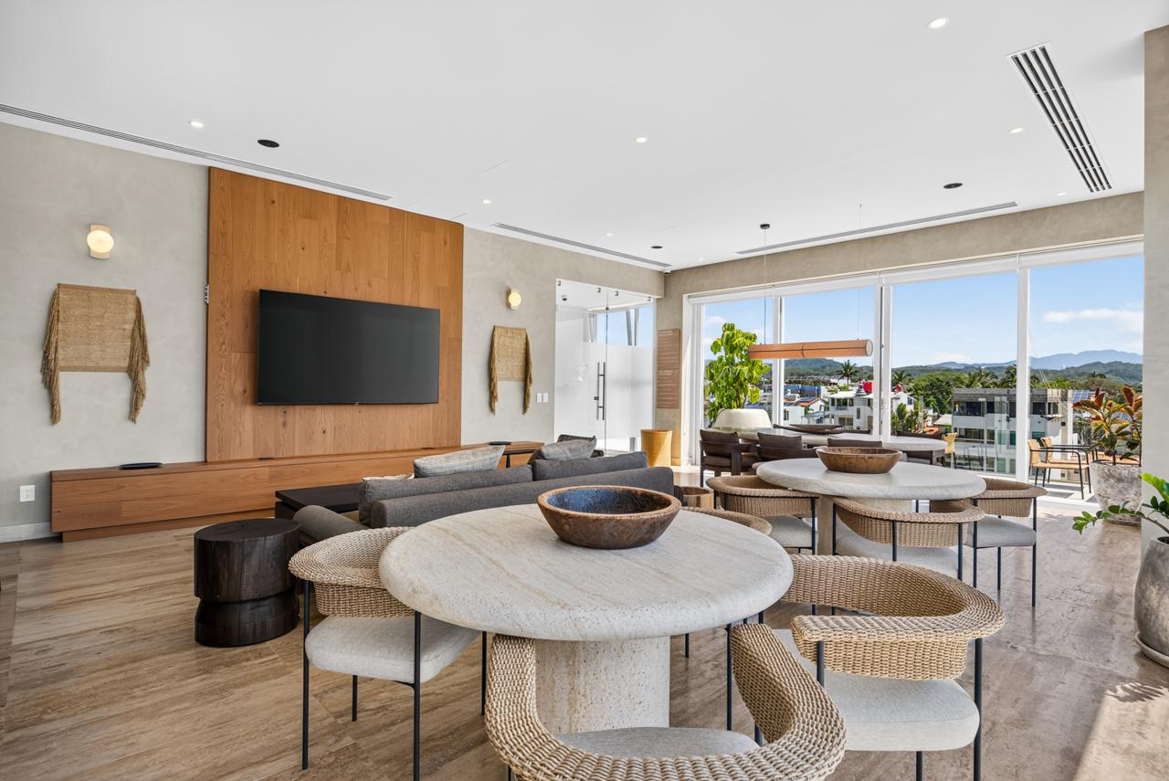 Clubhouse living area with wood-paneled media wall and travertine dining tables