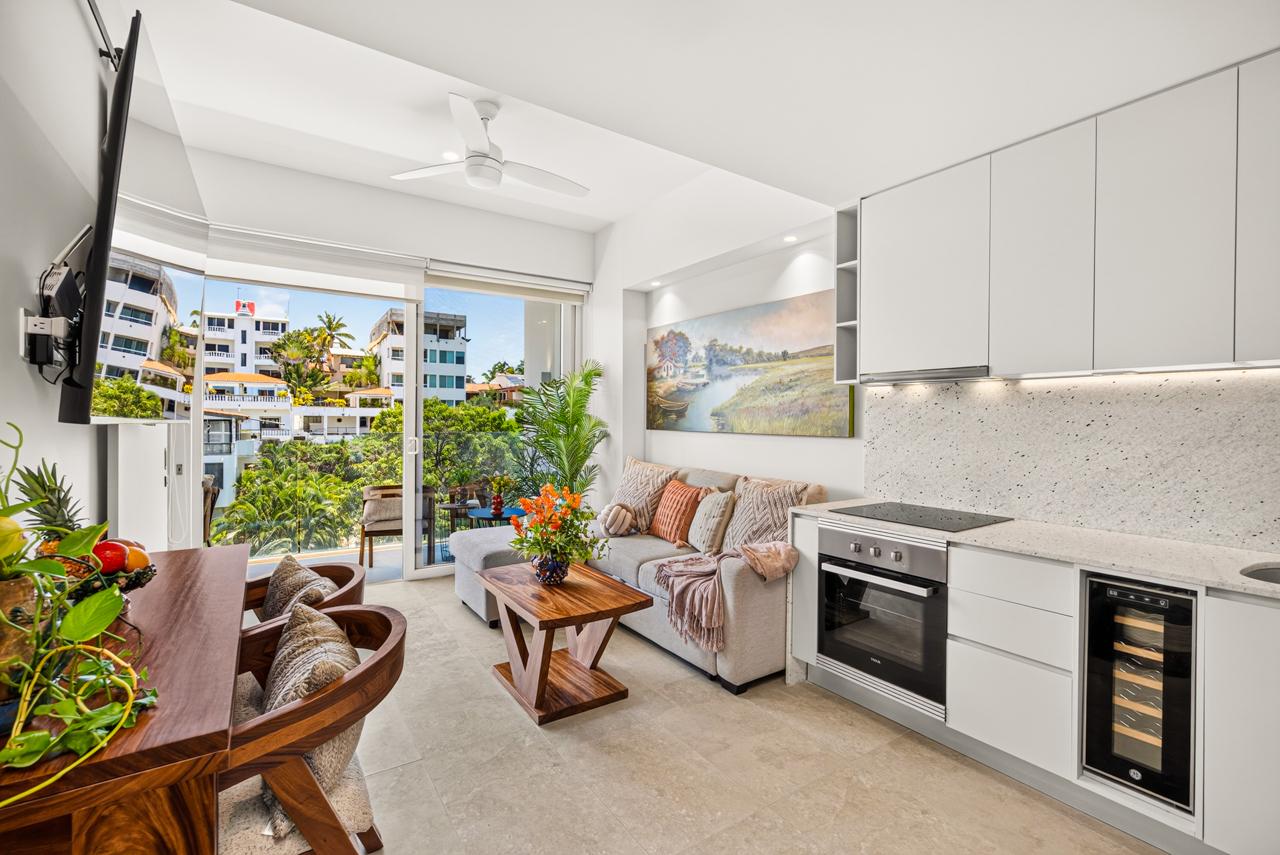 Bright living room with sofa, art and open balcony doors at Casa Nayah