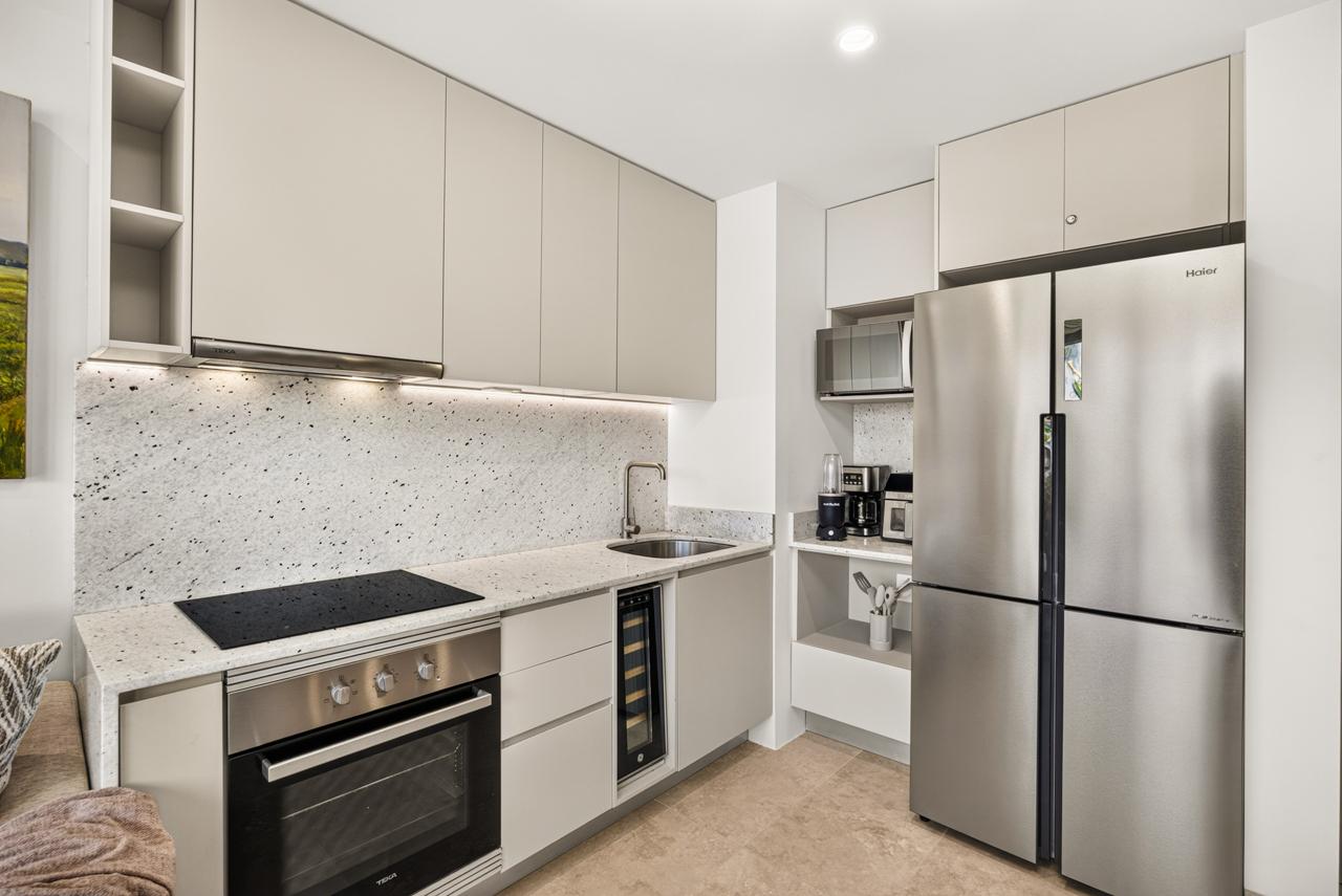 Full kitchen with induction cooktop, oven, wine fridge and stainless appliances